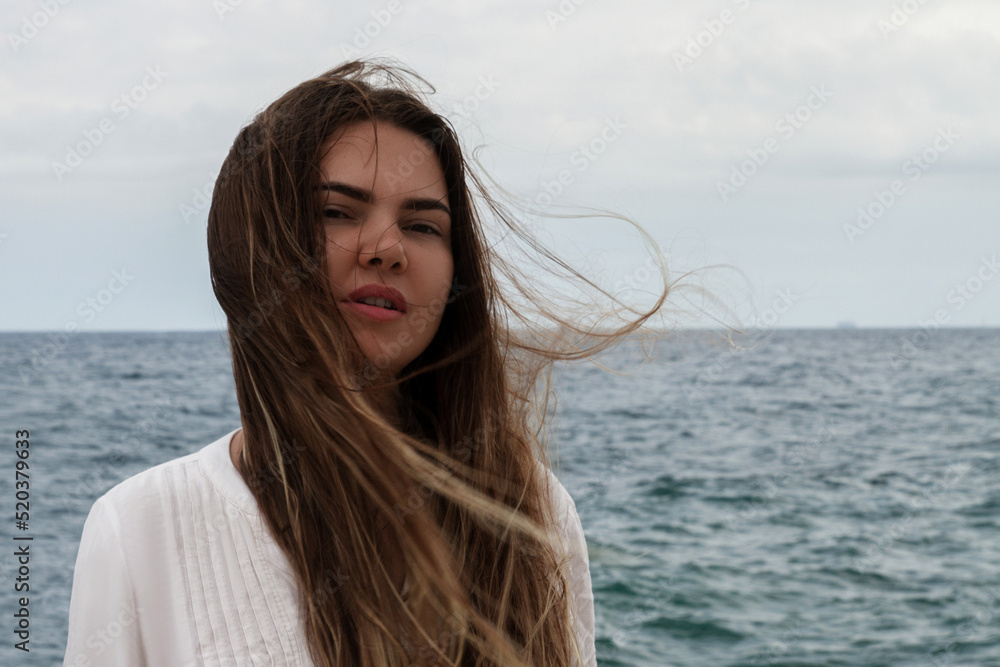 Girl with flowing hair against the background of the sea and the sky. Girl in a white dress. appeasement. Sea. Ocean.
