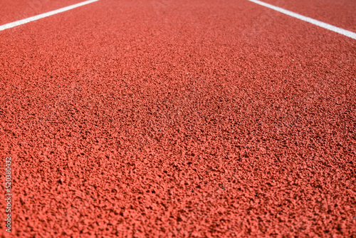 Sports stadium with red artificial rubber ground running tracks and white lines on it