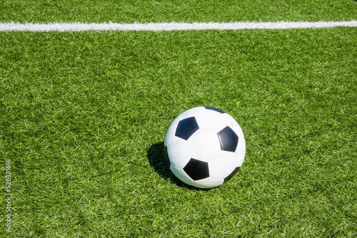 Football soccer sport background. Green artificial turf soccer field with white line  shadow from football goal net and soccer ball on sunny day outdoors. Top view