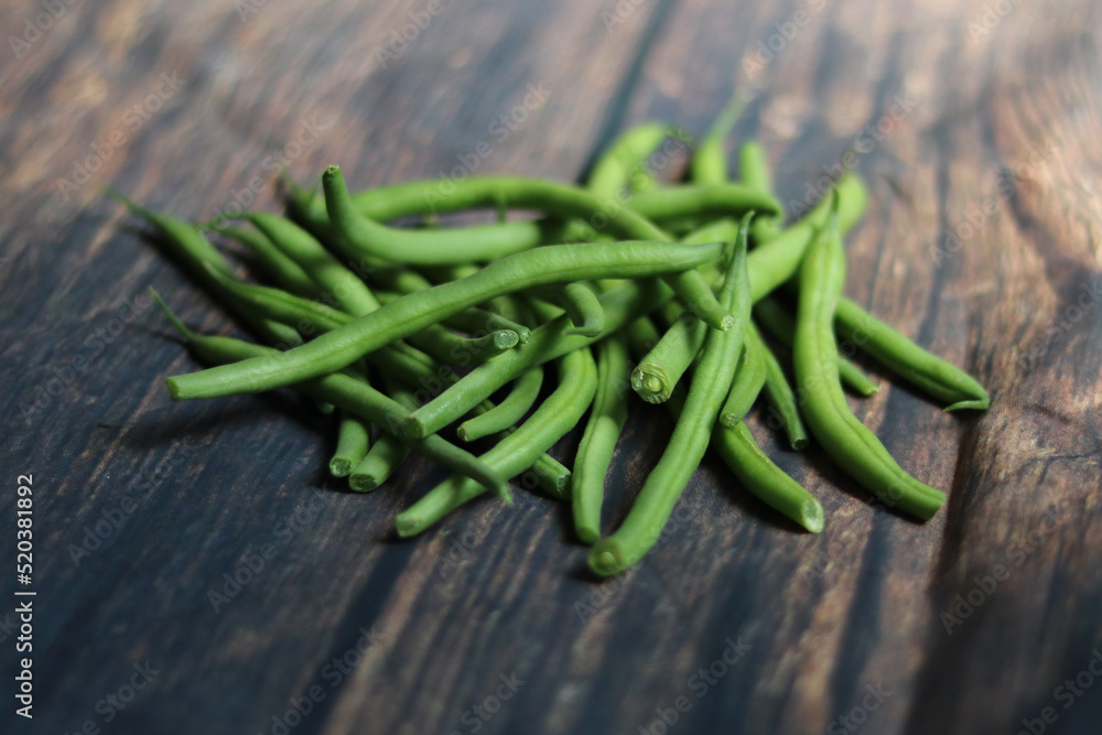 Pile of french beans lying on wooden rustic topped table Pile of french beans lying on wooden rustic topped table
