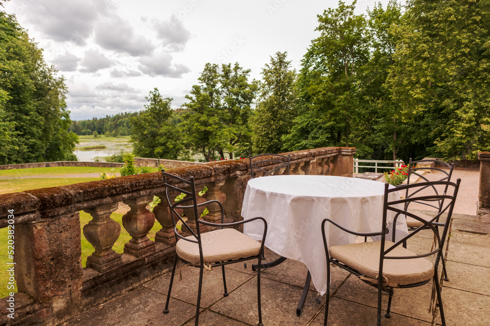 outdoor terrace with table and chairs against the background of the river and green trees
