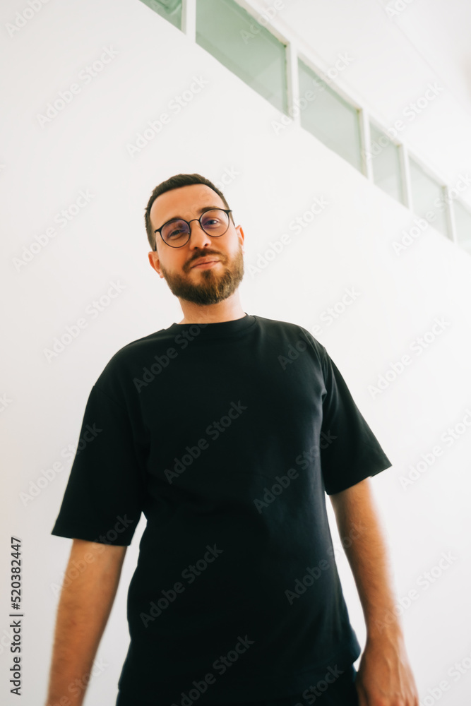 Portrait of stylish caucasian man in eyeglasses and black t shirt in bright living room. Portrait of stylish caucasian man in eyeglasses and black t shirt in bright living room.