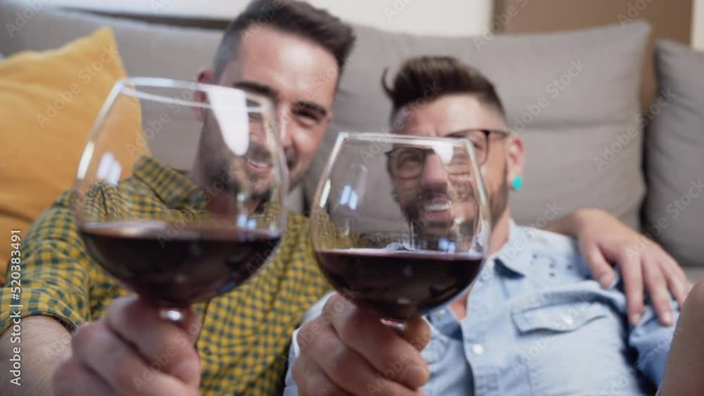 Gay couple in love sitting at home on the floor and toasting with red wine. High quality 4k footage Gay couple in love sitting at home on the floor and toasting with red wine. High quality 4k footage