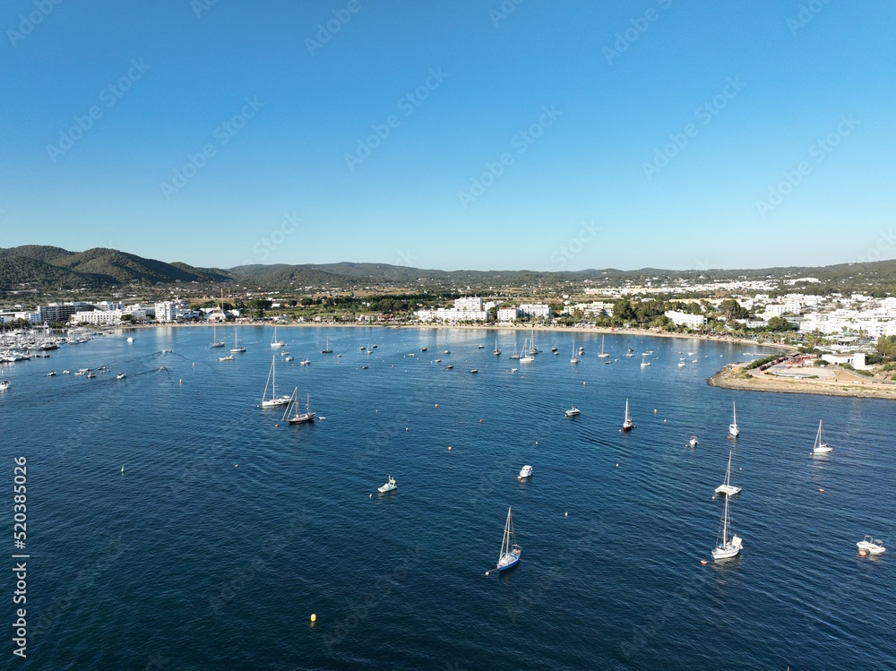 Obraz premium Aerial view of the coast of an island, full of boats and sailboats anchored off the beach.