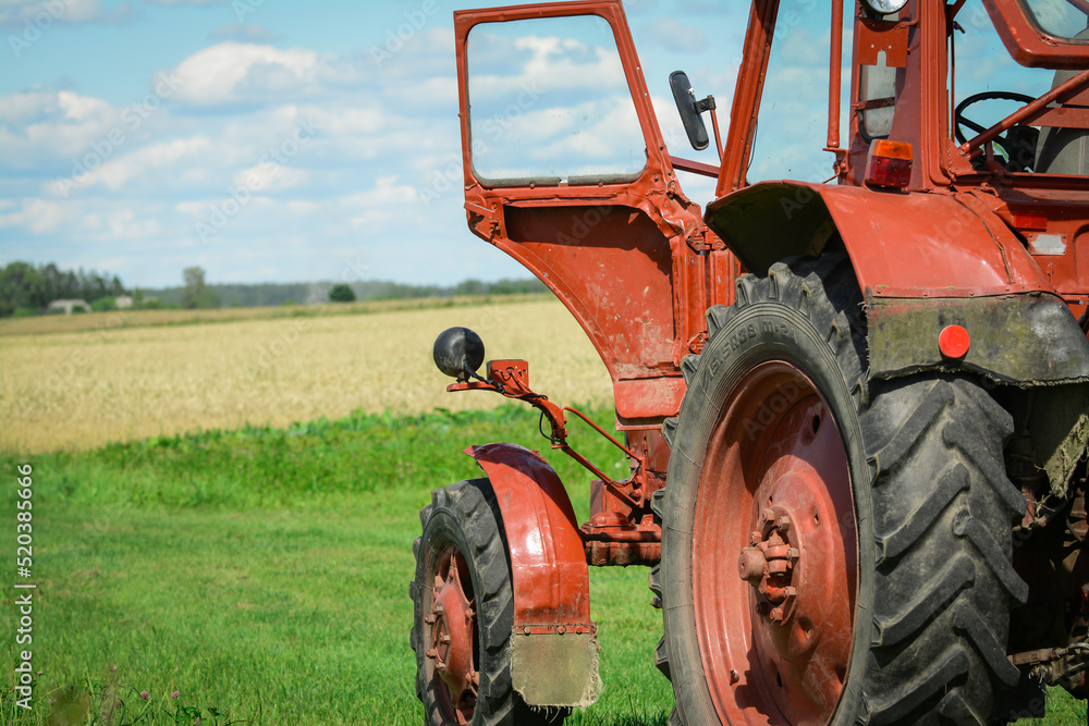 Obraz premium Red tractor in the fields is waiting for harvester 
