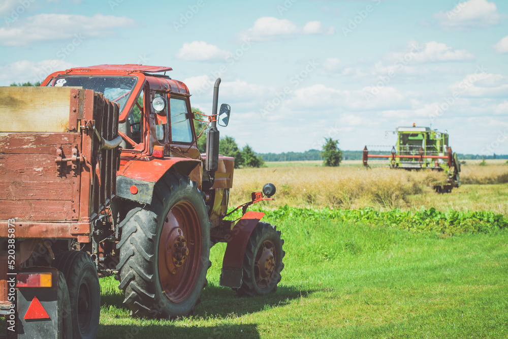 Red tractor in the fields is waiting for harvester Red tractor in the fields is waiting for harvester
