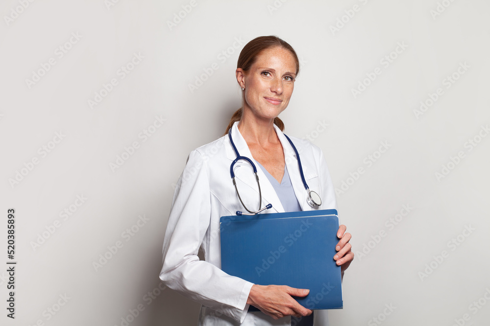 Cheerful young female doctor with stethoscope over neck looking at camera and smiling on white background Cheerful young female doctor with stethoscope over neck looking at camera and smiling on white background