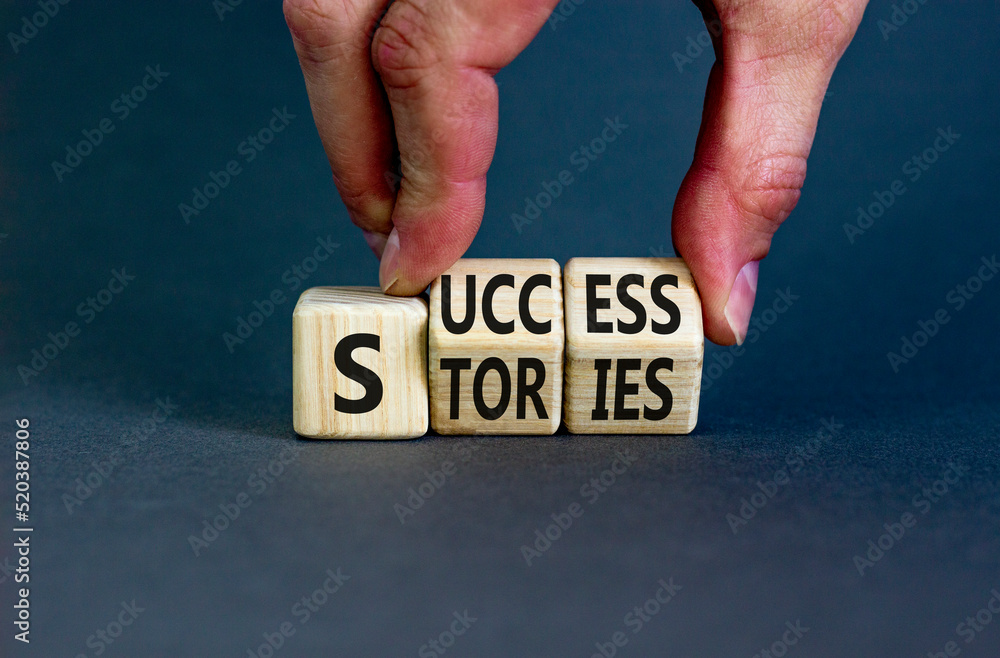 Success stories symbol. Concept words Success stories on wooden cubes. Businessman hand. Beautiful grey table grey background. Business and Success stories concept. Copy space. Success stories symbol. Concept words Success stories on wooden cubes. Businessman hand. Beautiful grey table grey background. Business and Success stories concept. Copy space.