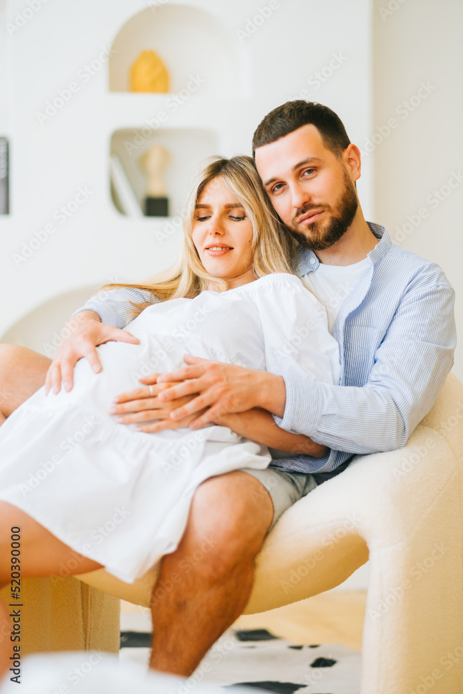 Fototapeta premium Future mother and father clasped pregnant big tummy. husband hugs pregnant wife. Happy family resting at home