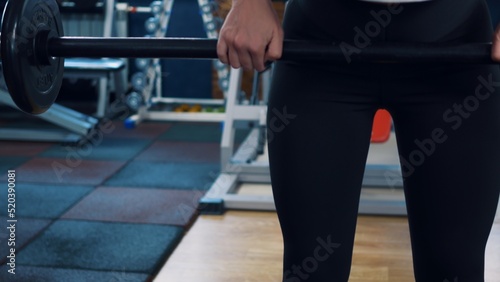 Athletic woman pumps muscles using a barbell with a weight. Classes in the gym using extreme bar weights. Reducing excess weight in the gym due to physical activity. Physical exercise.