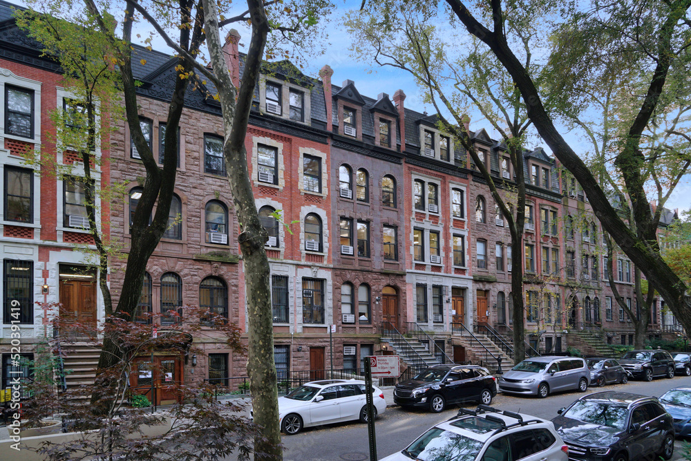 Residential street in New York with long row of old brownstone townhouses