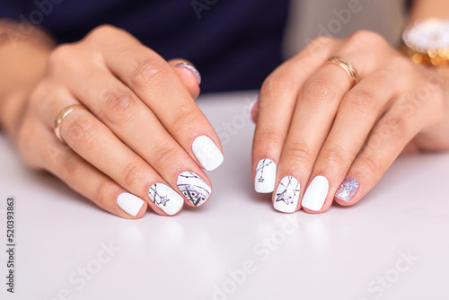  Beautiful female hands with fashion manicure nails, white and silver gel polish, stars design 