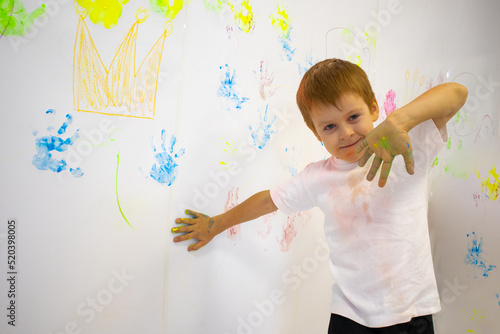 Wallpaper Mural a red-haired boy draws with his palms on a white wall in a white T-shirt .mock up of a white children's T-shirt. fun drawing Torontodigital.ca