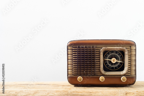 Retro radio receiver on a wooden surface and white background.  Vintage radio with copyspace.