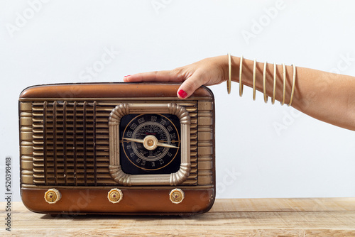 Hand with bracelets and painted nails on an old radio, with dials and push buttons. Listening music concept. Radio from 1950
