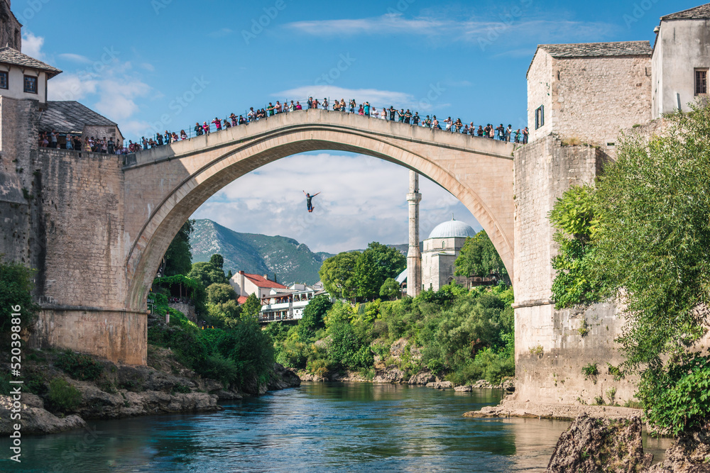 MOSTAR, BOSNIA AND HERZEGOVINA - September 21, 2021: Man is jumping diving from Stari most, Old Bridge, in Mostar. Bosnia and Herzegovina MOSTAR, BOSNIA AND HERZEGOVINA - September 21, 2021: Man is jumping diving from Stari most, Old Bridge, in Mostar. Bosnia and Herzegovina