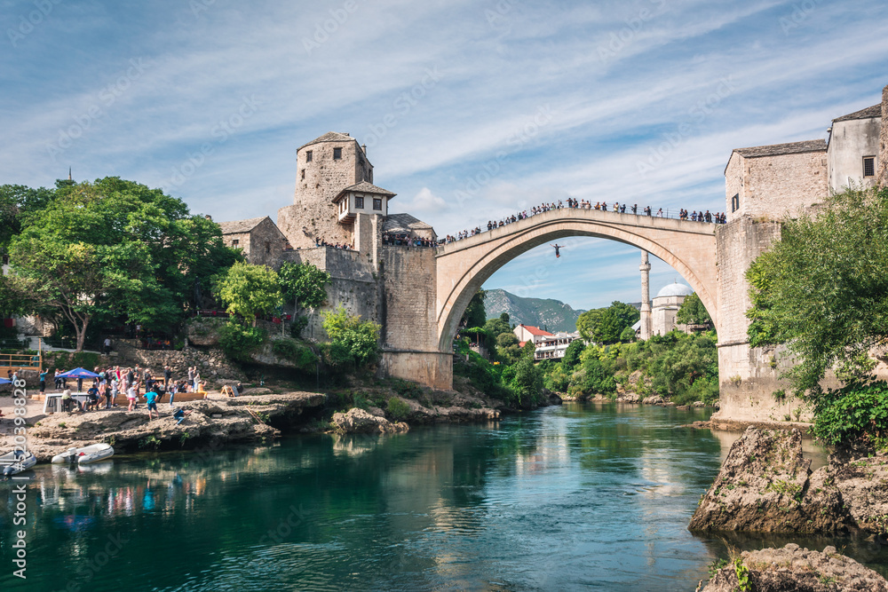 MOSTAR, BOSNIA AND HERZEGOVINA - September 22, 2021: Man is jumping diving from Stari most, Old Bridge, in Mostar. Bosnia and Herzegovina