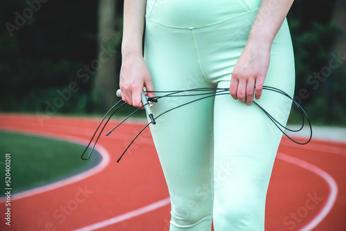 Close-up, skipping rope in female hands at the stadium.