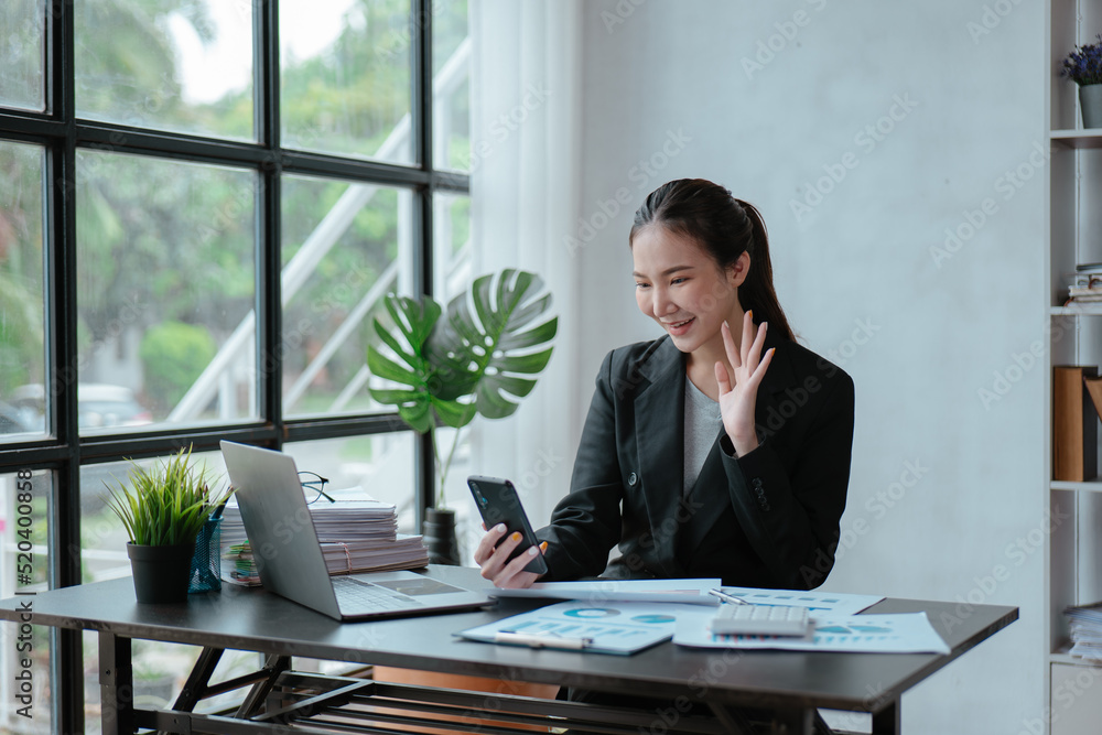 Young business woman discussing and talking with co-worker and client via smartphone and laptop with happy face. Young business woman discussing and talking with co-worker and client via smartphone and laptop with happy face.