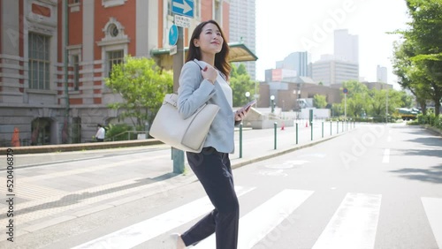 スマートフォンを見ながら歩くビジネスウーマン スマホ 女性