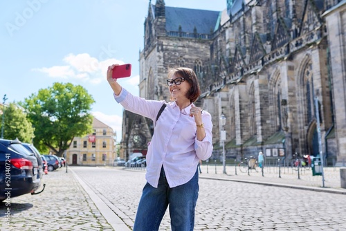 Woman tourist taking a selfie in front of an ancient European cathedral