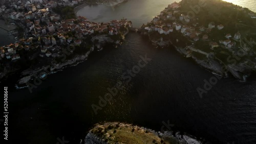 Flying over Kemere Bridge connecting Great island with Amasra city, Turkey. Aerial view of Black sea  calm harbor at sunset photo