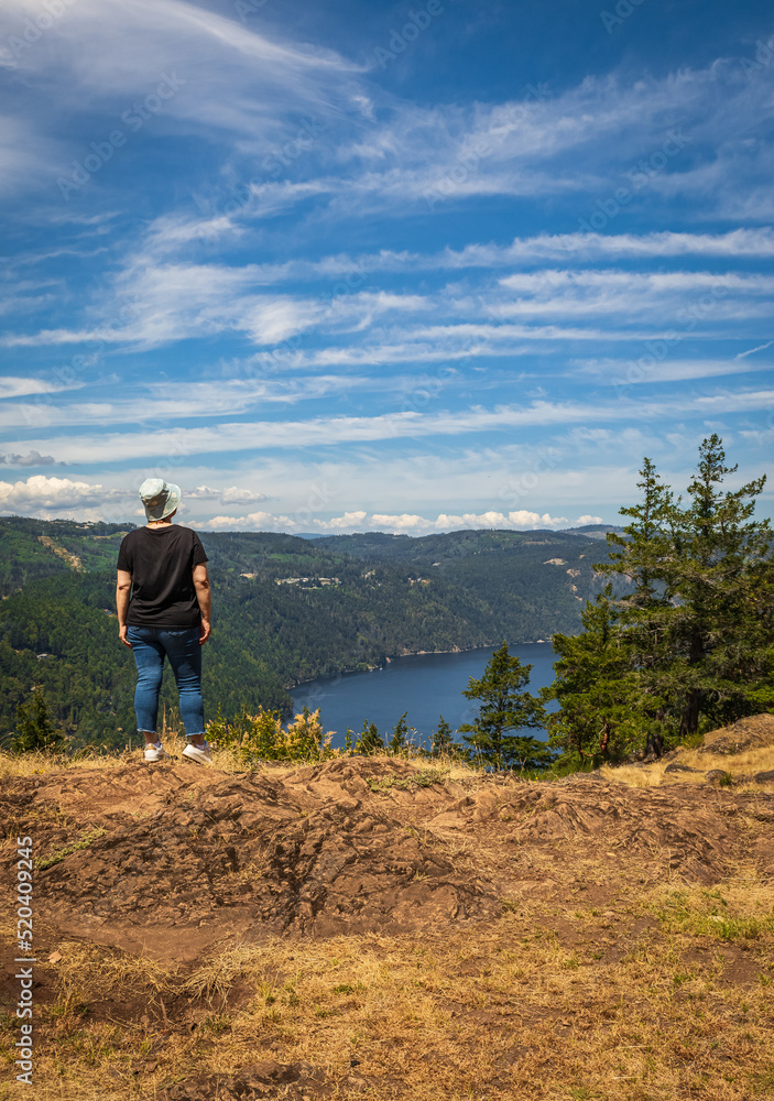 Woman standing on the edge of the cliff and enjoying view of the valley, river and mountains. Traveling along Canada