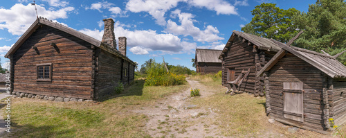 Photography Old log farm houses in a meadow, a sunny summer day in Stockholm
