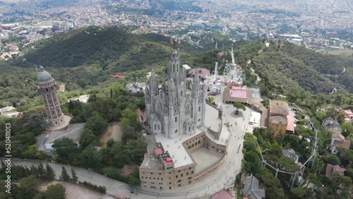 A camera drone flies around above the Temple of the Sacred Heart of Jesus and Tower of the Waters of Two Rivers, Barcelona, Spain photo
