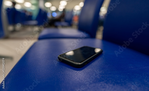 Close up view and low light. A smartphone is on seat in the room. Because people forget after sitting ready get up and leave.