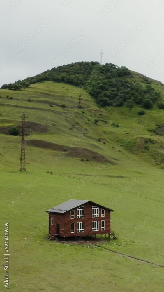 A lonely wooden house on stilts in field in a mountain valley among green hills A lonely wooden house on stilts in field in a mountain valley among green hills