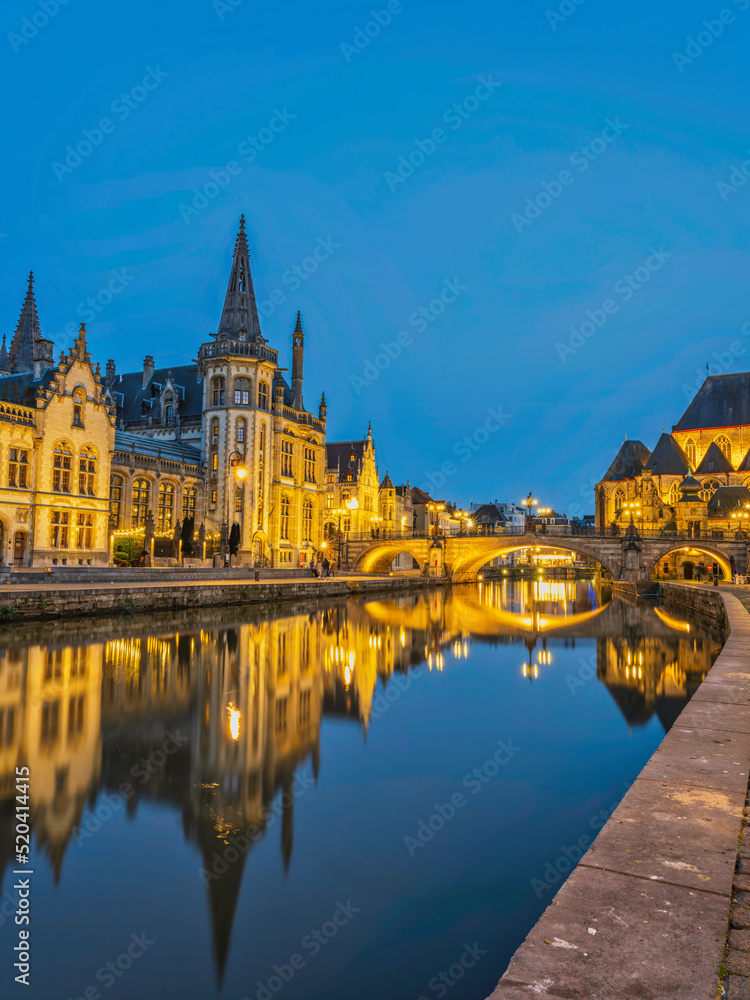 Historic medieval building and Arched stone bridge at night on Leie river in Ghent, Belgium