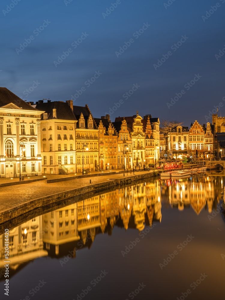 Historic medieval building illuminated at night on Leie river bank in Ghent, Belgium