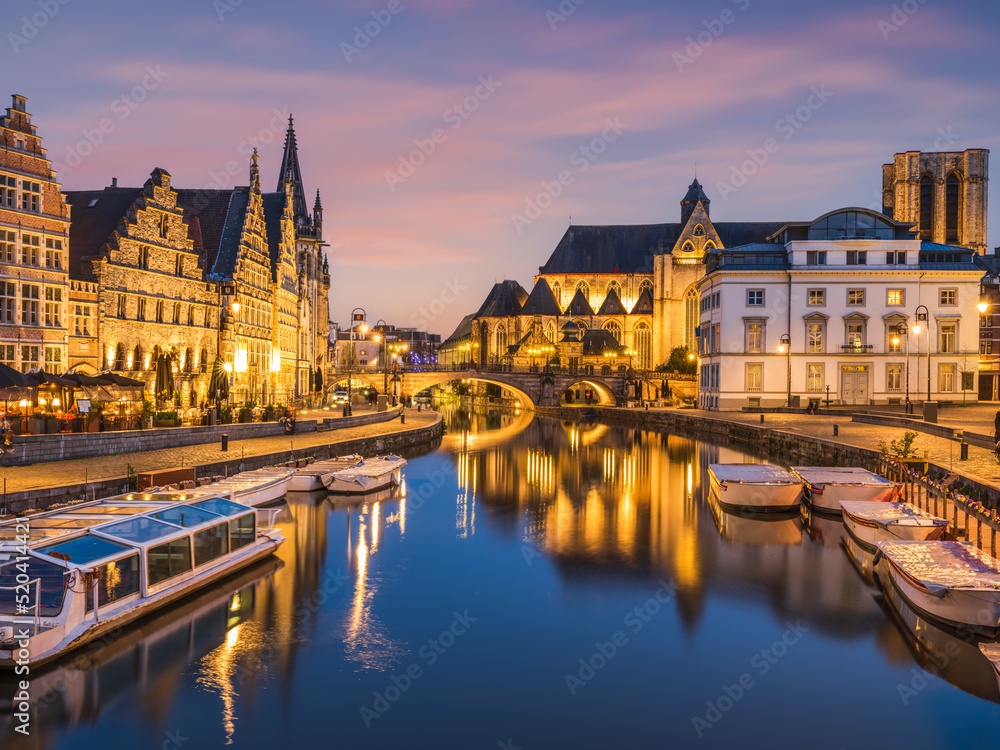 Historic medieval building illuminated at night on Leie river in Ghent, Belgium