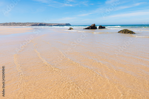 wide sandy beach with shallow water from incoming waves, coastal landscape Portugal