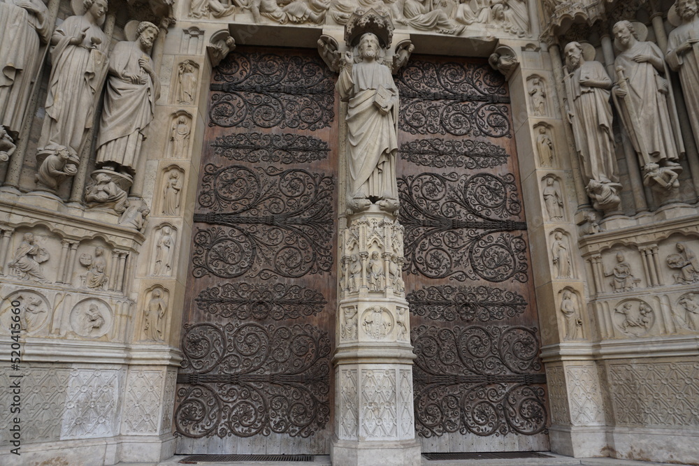 detail of the facade of the cathedral notre dame in downtown paris france with two wooden old doors