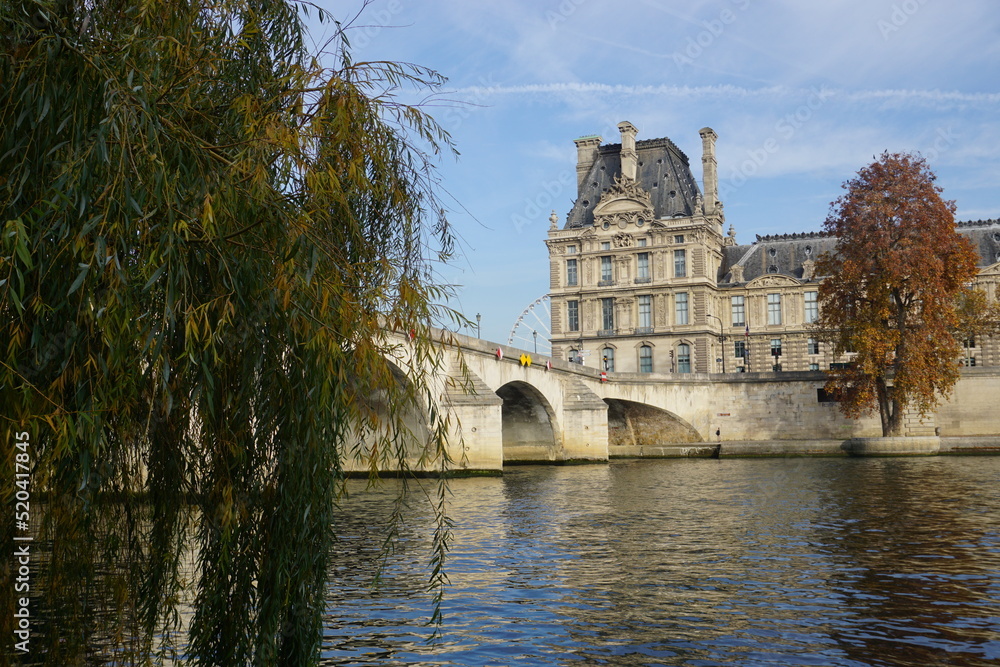 view of the louvre museum from the seine river by the old stone bridge in paris france