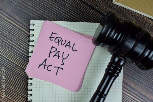 Concept of Equal Pay Act write on sticky notes with gavel isolated on Wooden Table.
