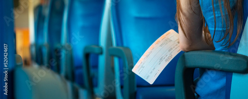 A woman with a ticket is sitting in a clean and empty train