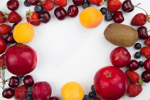 Different fruits and berries lie on a white background on the sides of the photo  forming a frame with an empty space in the middle for the text. High quality photo