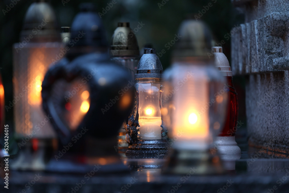 Świeczka na grobie osoby bliskiej świeci podczas święta zmarłych.  - obrazy, fototapety, plakaty 