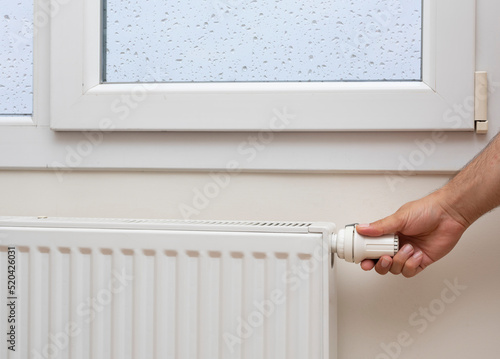 Man's hand adjusting the temperature of a radiator. front view