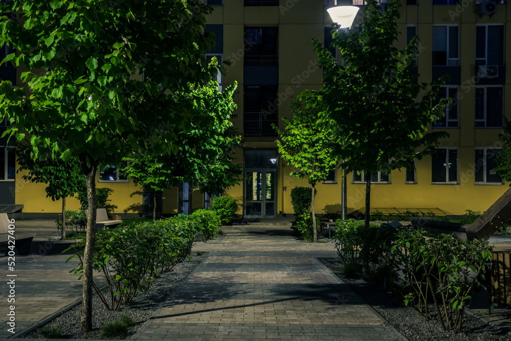 Night park paths and colored houses at summer night. Night paths, benches and lanterns in a beautiful residential complex. Night summer park with lanterns and benches. Kyiv. Ukraine