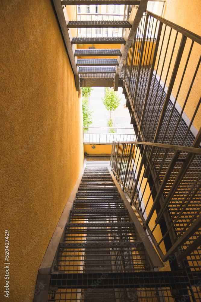 Obraz premium Internal metal fire escapes of a modern building, modern metal ladder. Fire escape in a modern house with yellow walls