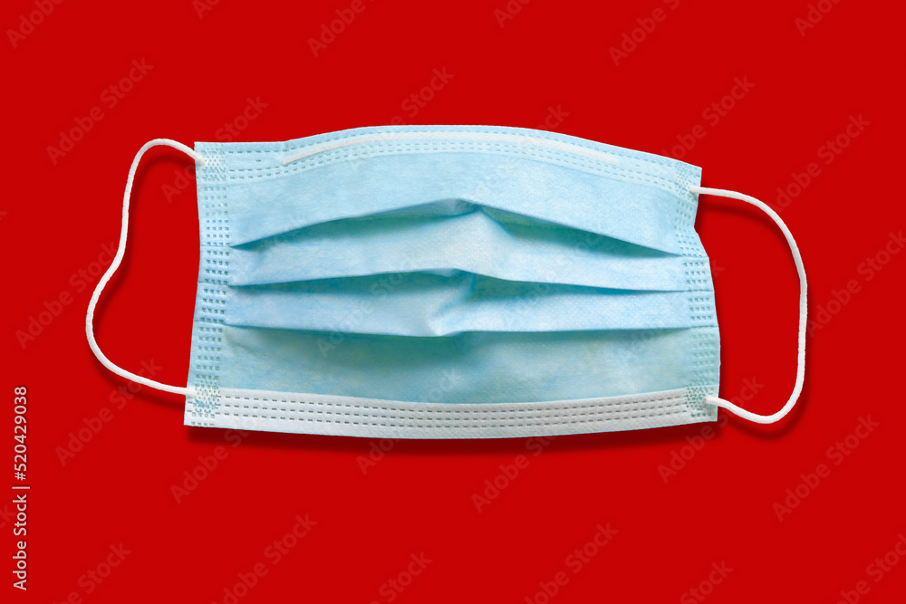 Medical mask. Disposable medical surgical mask. Protection against respiratory infections. Isolate on red background. Health care and medical concept Medical mask. Disposable medical surgical mask. Protection against respiratory infections. Isolate on red background. Health care and medical concept