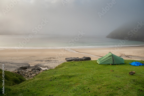 Tents on a grass by the ocean with amazing nature scenery. Keem bay and beach, Ireland. Famous travel area for water sport and hiking with stunning nature view. Calm mood. photo