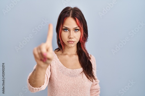 Young caucasian woman wearing pink sweater over isolated background pointing with finger up and angry expression, showing no gesture