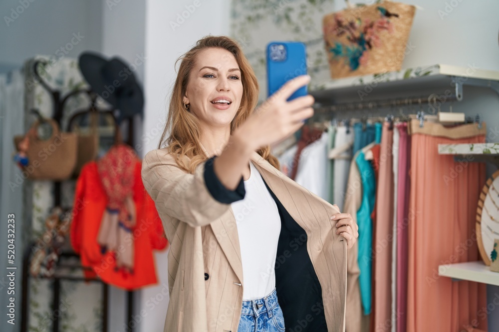 Young blonde woman customer having video call at clothing store