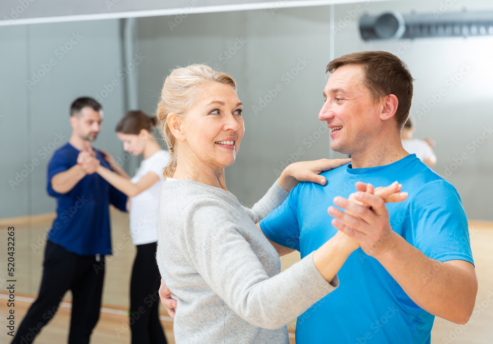 Fototapeta premium Smiling middle aged woman enjoying dance with partner in dancing class