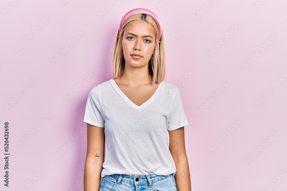 Beautiful blonde woman wearing casual white t shirt relaxed with serious expression on face. simple and natural looking at the camera. Beautiful blonde woman wearing casual white t shirt relaxed with serious expression on face. simple and natural looking at the camera.